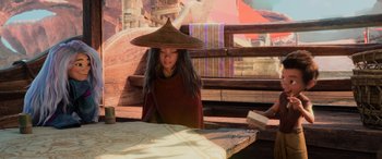 Movie still from “Raya and the Last Dragon” (2021), directed by Don Hall – A woman wearing a hat sitting at a table; Medium shot, Over the shoulder angle