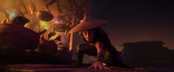 Movie still from “Raya and the Last Dragon” (2021), directed by Don Hall – A person crouching down wearing a straw hat; Wide shot, Low angle