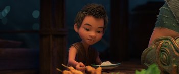 Movie still from “Raya and the Last Dragon” (2021), directed by Don Hall – A young boy is sitting at a table with a plate of food; Close Up shot, High angle