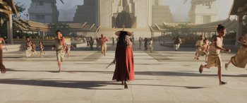 Movie still from “Raya and the Last Dragon” (2021), directed by Don Hall – A woman in a long red coat and a hat walking down a street; Extreme Wide shot, Over the shoulder angle