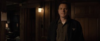 Movie still from “Raymond & Ray” (2022), directed by Rodrigo García – A man standing in front of a wall with lights; Medium shot, Over the shoulder angle