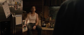 Movie still from “Raymond & Ray” (2022), directed by Rodrigo García – A man sitting on a counter in a kitchen; Medium shot, Over the shoulder angle