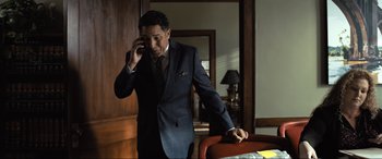 Movie still from “Raymond & Ray” (2022), directed by Rodrigo García – A man in a suit and tie talking on a cell phone; Medium shot, High angle