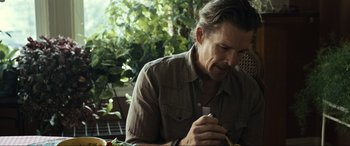 Movie still from “Raymond & Ray” (2022), directed by Rodrigo García – A person sitting at a table holding a cell phone; Close Up shot, High angle