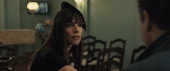 Movie still from “Raymond & Ray” (2022), directed by Rodrigo García – A woman wearing a hat sitting in front of a bunch of chairs; Close Up shot, Over the shoulder angle