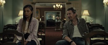 Movie still from “Raymond & Ray” (2022), directed by Rodrigo García – A man and a woman are sitting in a room together; Medium shot, Over the shoulder angle