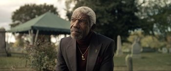 Movie still from “Raymond & Ray” (2022), directed by Rodrigo García – An older man in a suit and a cross on his neck; Close Up shot, Low angle