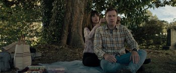 Movie still from “Raymond & Ray” (2022), directed by Rodrigo García – A man and a woman sitting on the ground in front of a tree; Medium shot, High angle