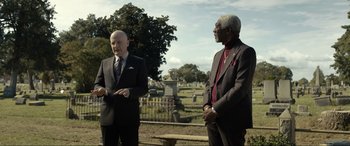 Movie still from “Raymond & Ray” (2022), directed by Rodrigo García – Two men in suits standing in a cemetery; Medium shot, Over the shoulder angle