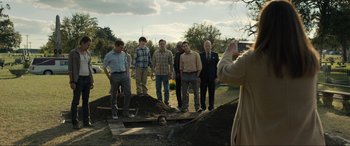 Movie still from “Raymond & Ray” (2022), directed by Rodrigo García – A group of men standing around a dirt pile; Wide shot, High angle