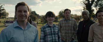 Movie still from “Raymond & Ray” (2022), directed by Rodrigo García – A group of people standing in the grass; Medium shot, Over the shoulder angle