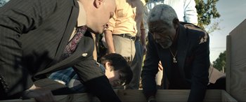 Movie still from “Raymond & Ray” (2022), directed by Rodrigo García – A group of people standing around a wooden table; Medium shot, Over the shoulder angle