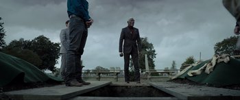 Movie still from “Raymond & Ray” (2022), directed by Rodrigo García – A man in a suit and tie standing next to another man; Wide shot, Low angle