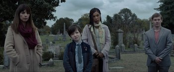 Movie still from “Raymond & Ray” (2022), directed by Rodrigo García – A woman and a boy standing next to each other in a cemetery; Medium shot, Over the shoulder angle