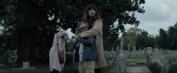 Movie still from “Raymond & Ray” (2022), directed by Rodrigo García – A woman hugging a child in a cemetery; Medium shot, Low angle