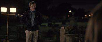 Movie still from “Raymond & Ray” (2022), directed by Rodrigo García – A man standing in the dark in front of a cemetery; Medium shot, Over the shoulder angle