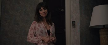 Movie still from “Raymond & Ray” (2022), directed by Rodrigo García – A woman standing in front of a door smiling for the camera; Medium shot, Over the shoulder angle