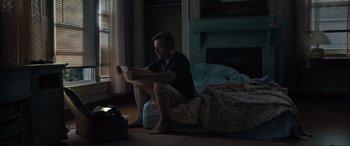 Movie still from “Raymond & Ray” (2022), directed by Rodrigo García – A man sitting on the floor in front of a fire place; Medium shot, Low angle