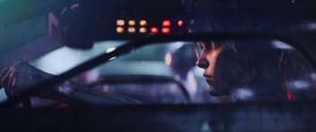 Movie still from “Ready Player One” (2018), directed by Steven Spielberg – A woman looking out of the window of a car at night; Close Up shot, Over the shoulder angle