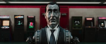 Movie still from “Ready Player One” (2018), directed by Steven Spielberg – A man in a suit and tie standing in front of a building; Close Up shot, Low angle