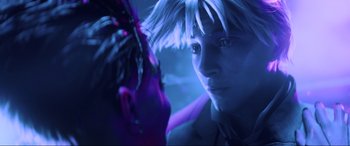 A man is looking into a mirror in a dark room