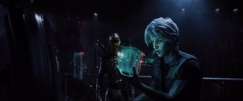 Movie still from “Ready Player One” (2018), directed by Steven Spielberg – A woman holding a cell phone in front of a robot; Medium shot, Over the shoulder angle