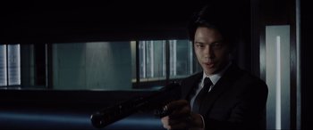 Movie still from “Ready Player One” (2018), directed by Steven Spielberg – A man in a suit and tie holding a gun; Close Up shot, Low angle