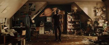 Movie still from “Ready Player One” (2018), directed by Steven Spielberg – A man standing in a room with a painting on the wall behind him; Wide shot, Low angle