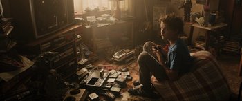 Movie still from “Ready Player One” (2018), directed by Steven Spielberg – A man sitting on the floor in front of a pile of electronics; Medium shot, High angle