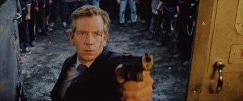Movie still from “Ready Player One” (2018), directed by Steven Spielberg – A man holding a gun in front of a group of onlookers; Close Up shot, Over the shoulder angle