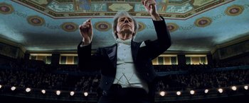 Movie still from “Red Dragon” (2002), directed by Brett Ratner – An older man is holding a conductor's baton in his hands; Medium shot, Low angle