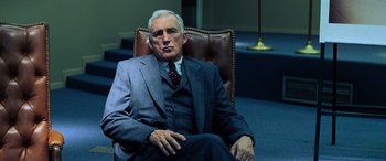 Movie still from “Red Dragon” (2002), directed by Brett Ratner – An older man in a suit sitting in a chair; Medium shot, Low angle