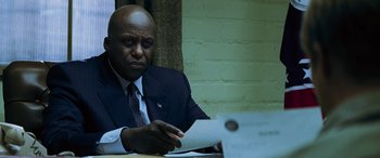 Movie still from “Red Dragon” (2002), directed by Brett Ratner – A man sitting at a table with papers in front of him; Close Up shot, Low angle
