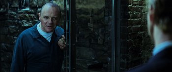 Movie still from “Red Dragon” (2002), directed by Brett Ratner – A man in a suit and tie standing in front of a building; Medium shot, Low angle