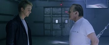 Movie still from “Red Dragon” (2002), directed by Brett Ratner – A man standing next to another man in an empty room; Medium shot, Over the shoulder angle