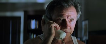 Movie still from “Red Dragon” (2002), directed by Brett Ratner – An older man talking on a phone while wearing a white shirt; Close Up shot, Low angle