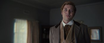 Movie still from “Redeeming Love” (2022), directed by D.J. Caruso – A man in a suit and tie standing in a room; Close Up shot, Low angle