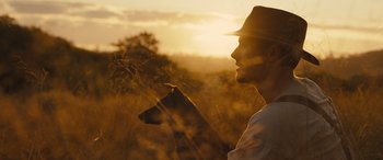 Movie still from “Redeeming Love” (2022), directed by D.J. Caruso – A man and a dog in a field at sunset; Close Up shot, Low angle