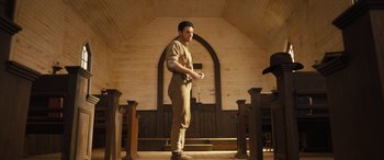 Movie still from “Redeeming Love” (2022), directed by D.J. Caruso – A man standing in front of a wooden wall; Wide shot, Low angle
