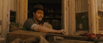 Movie still from “Redeeming Love” (2022), directed by D.J. Caruso – A man wearing a cowboy hat sitting at a table; Close Up shot, Over the shoulder angle