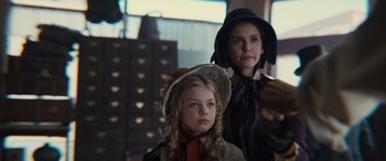 Movie still from “Redeeming Love” (2022), directed by D.J. Caruso – A woman and a girl wearing hats in a room; Medium shot, Over the shoulder angle