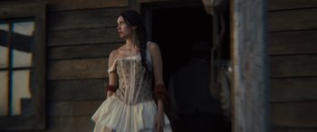 Movie still from “Redeeming Love” (2022), directed by D.J. Caruso – A woman in a white dress standing in front of a building; Medium shot, Low angle