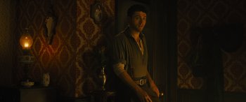 Movie still from “Redeeming Love” (2022), directed by D.J. Caruso – A man standing in front of a table with a vase of flowers; Medium shot, Low angle