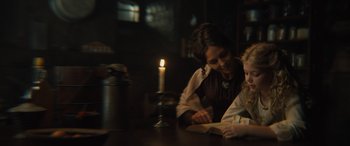 Movie still from “Redeeming Love” (2022), directed by D.J. Caruso – A woman and a child are reading a book by a candle light; Medium shot, Over the shoulder angle