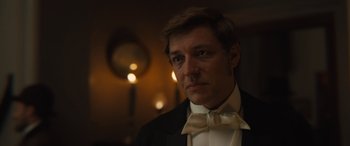 Movie still from “Redeeming Love” (2022), directed by D.J. Caruso – A person wearing a suit and bow tie; Close Up shot, Over the shoulder angle