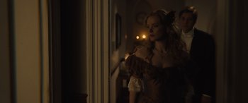 Movie still from “Redeeming Love” (2022), directed by D.J. Caruso – A woman standing in front of a window in a dark room; Medium shot, Over the shoulder angle