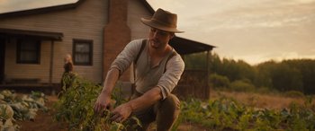 Movie still from “Redeeming Love” (2022), directed by D.J. Caruso – A man wearing a hat and working in a garden; Medium shot, Low angle
