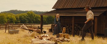 Movie still from “Redeeming Love” (2022), directed by D.J. Caruso – A woman standing in front of a log pile; Wide shot, Low angle