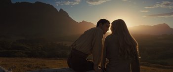 Movie still from “Redeeming Love” (2022), directed by D.J. Caruso – A man and a woman sitting on the ground in front of mountains; Medium shot, Over the shoulder angle