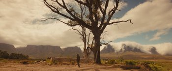 Movie still from “Redeeming Love” (2022), directed by D.J. Caruso – A man standing in front of a large tree in the desert; Extreme Wide shot, Low angle
